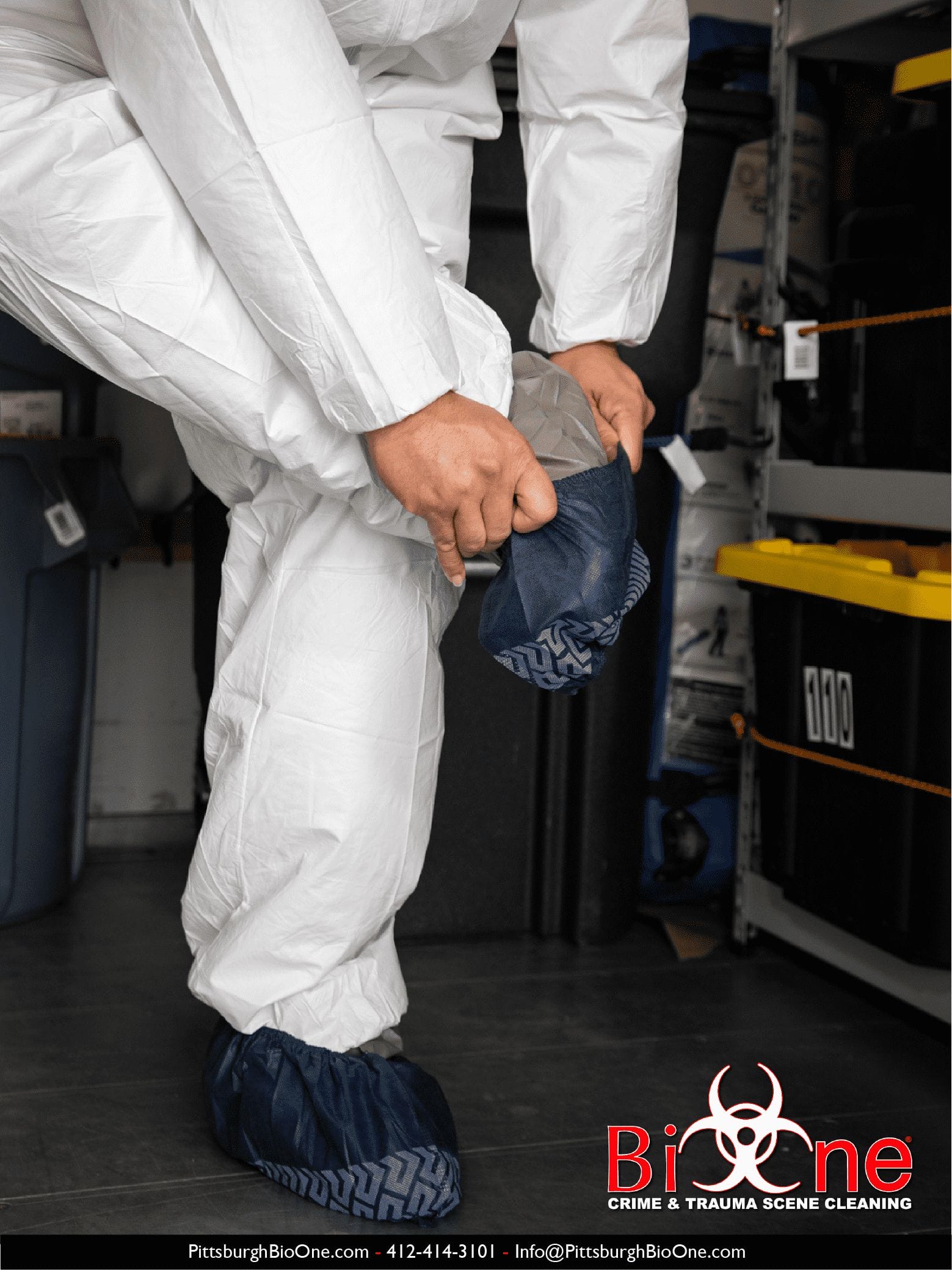Image shows Bio-One technician gearing up with PPE (hazmat and shoewear).